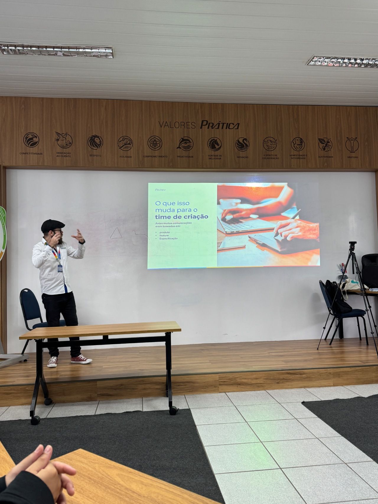 Uma pessoa vestindo camisa branca e calça preta apresenta um slide sobre cerâmica
