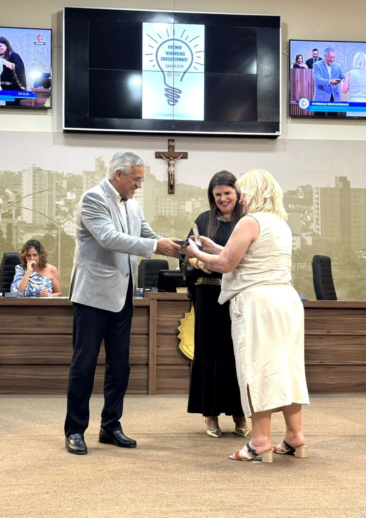 Um homem está dando um troféu para uma mulher em uma sala.
