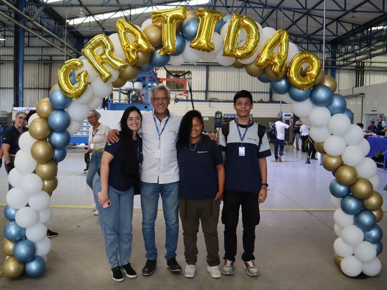 Um grupo de pessoas em pé sob um arco de balões que diz gratidao