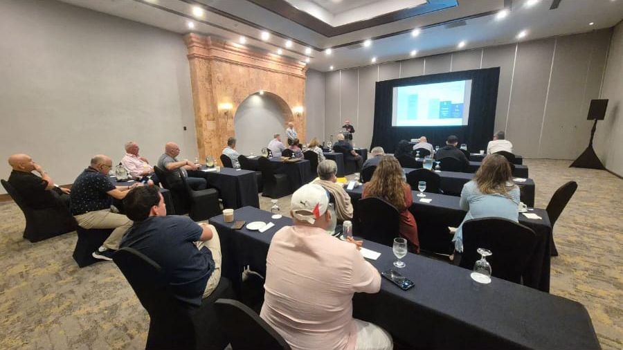 Sala de conferência com participantes assistindo a uma apresentação em uma tela.