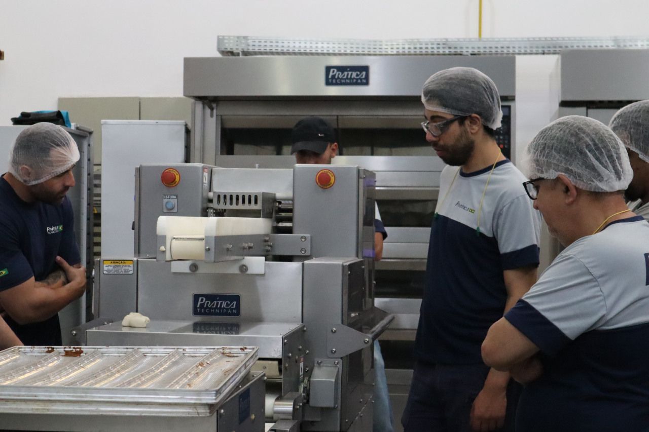 Um grupo de homens está em volta de uma máquina em uma cozinha.