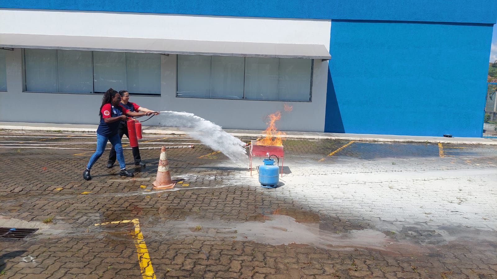 Duas pessoas estão jogando água em um incêndio em um estacionamento.