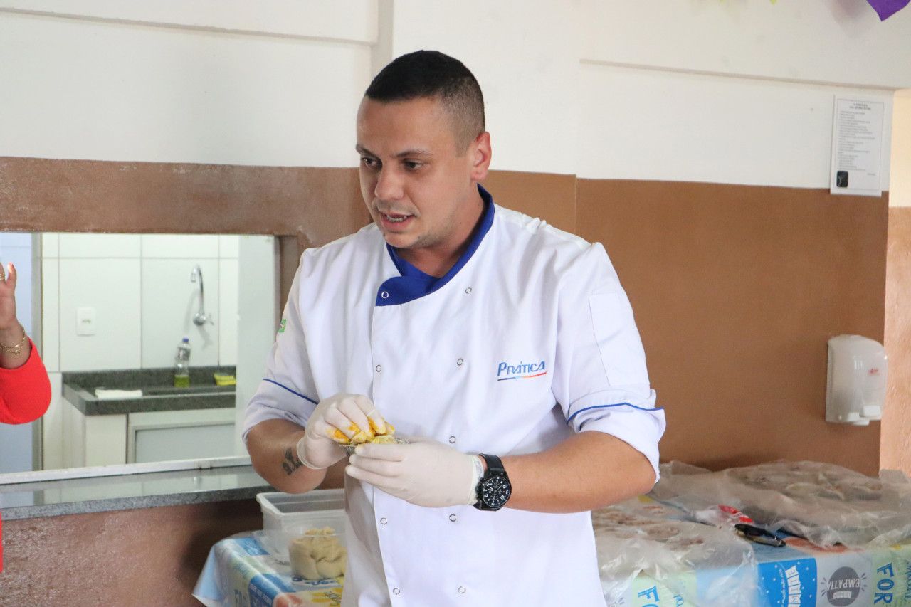 Um homem com uniforme de chef está em pé na cozinha.