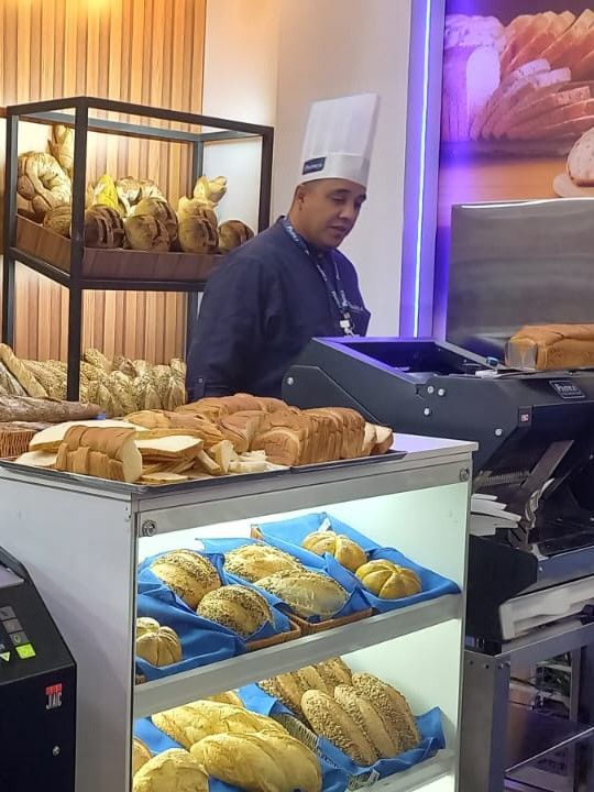 Um homem com chapéu de chef está trabalhando em uma padaria