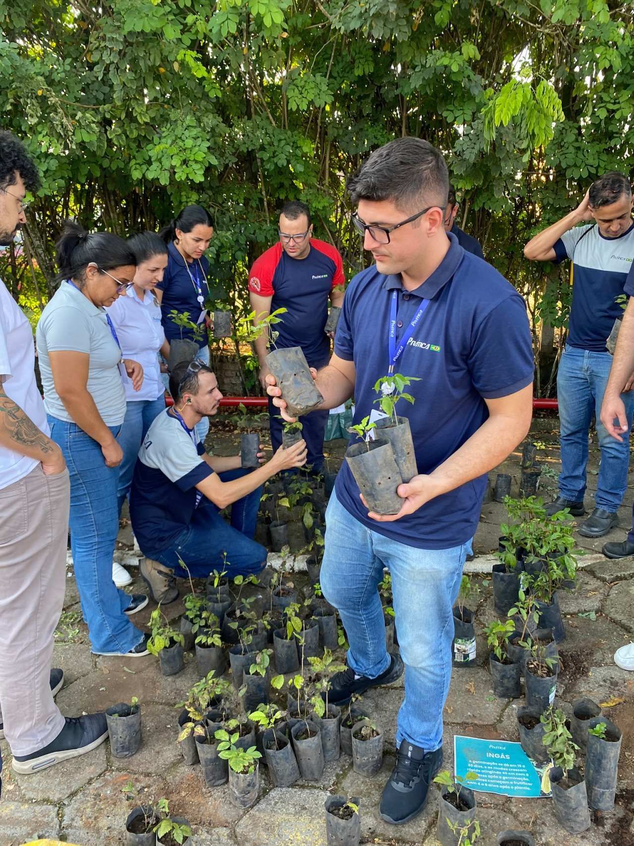 Um homem está segurando uma planta em vaso na frente de um grupo de pessoas.