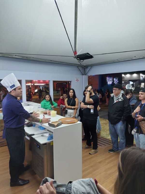 Um homem com chapéu de chef está fazendo uma apresentação para um grupo de pessoas