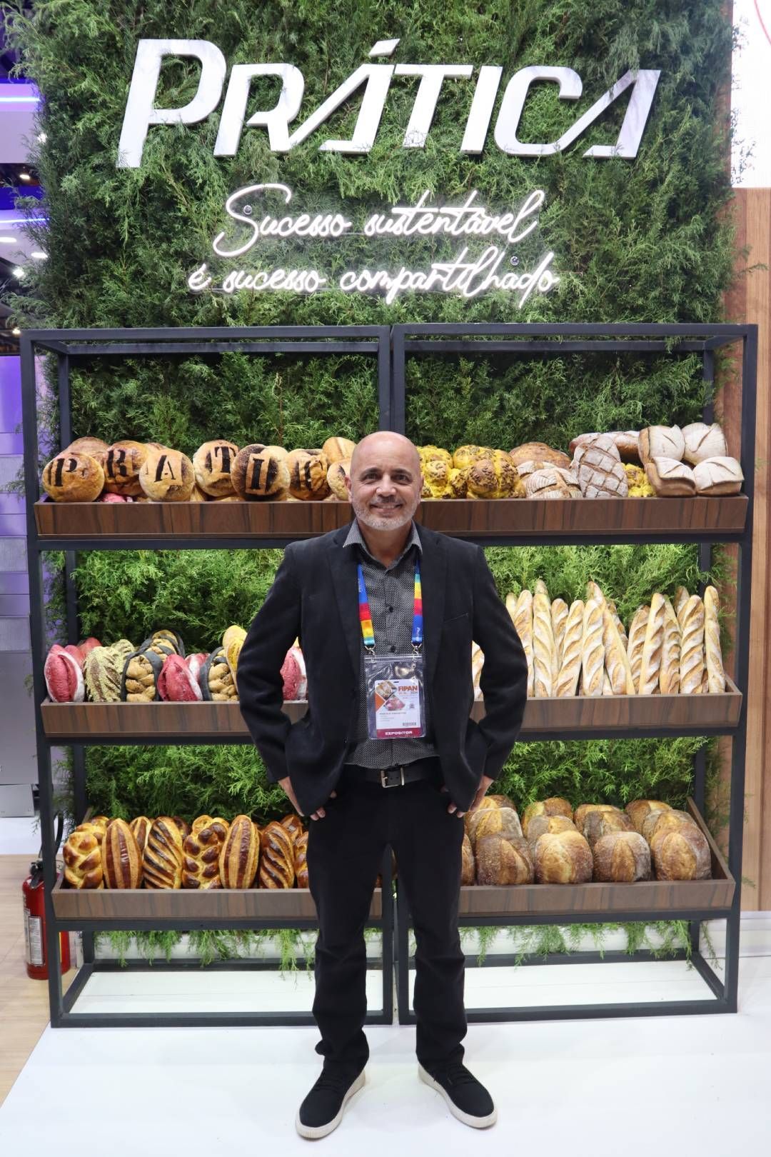 Um homem de terno está parado em frente a uma exposição de comida.
