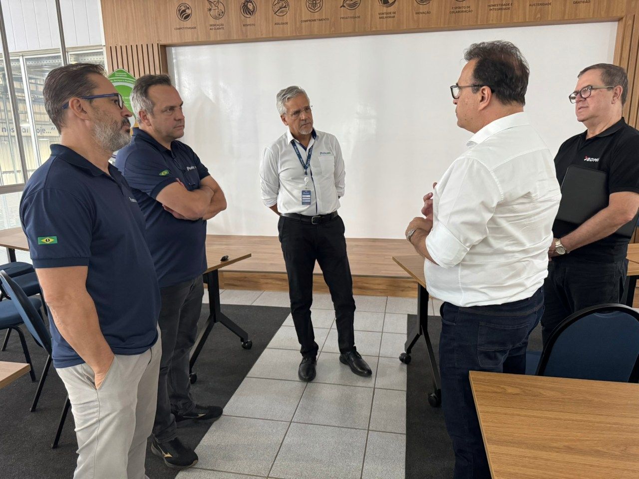 Um grupo de homens está em uma sala conversando entre si.