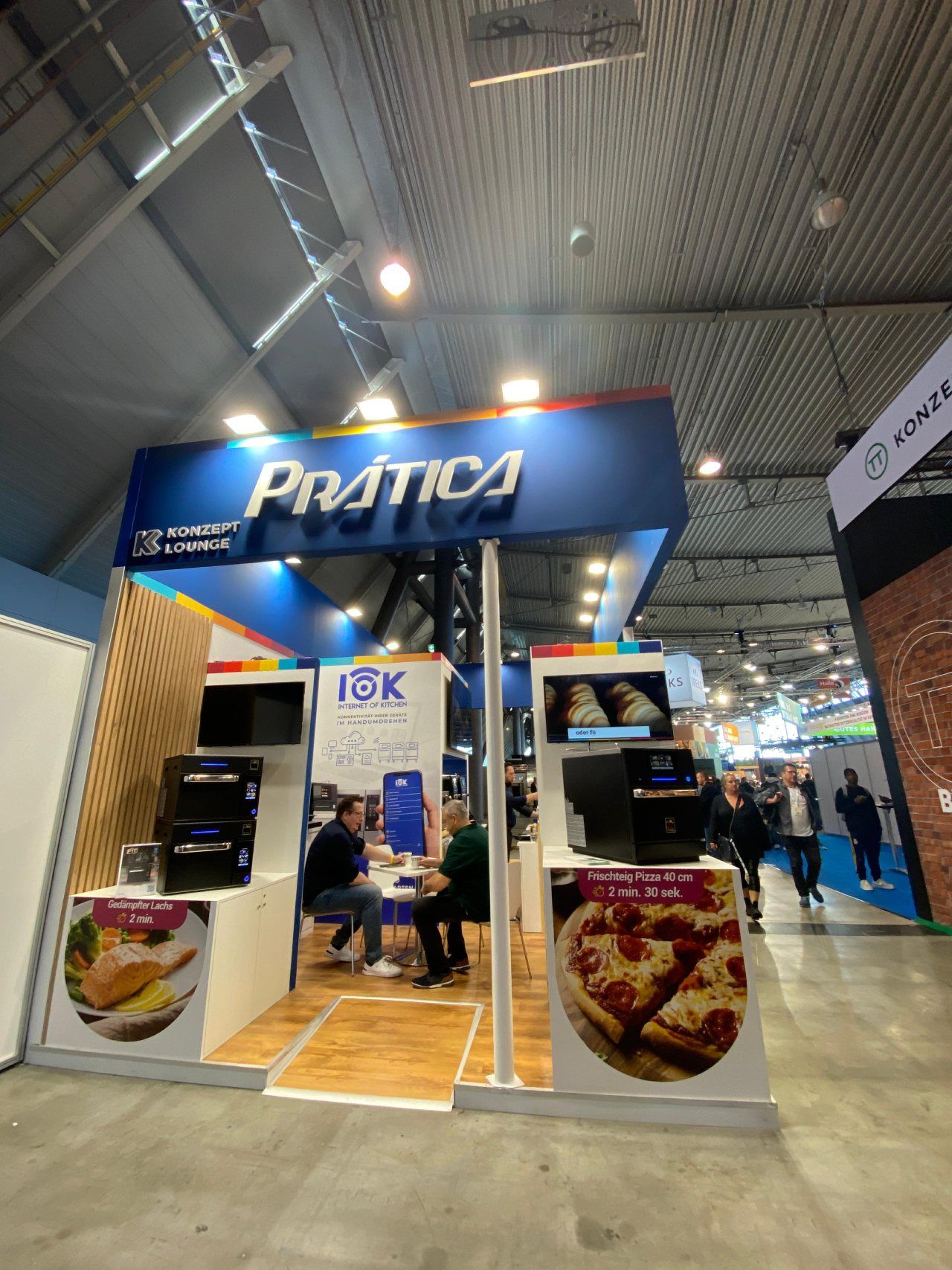 As pessoas estão sentadas em uma mesa sob uma placa que diz pratica