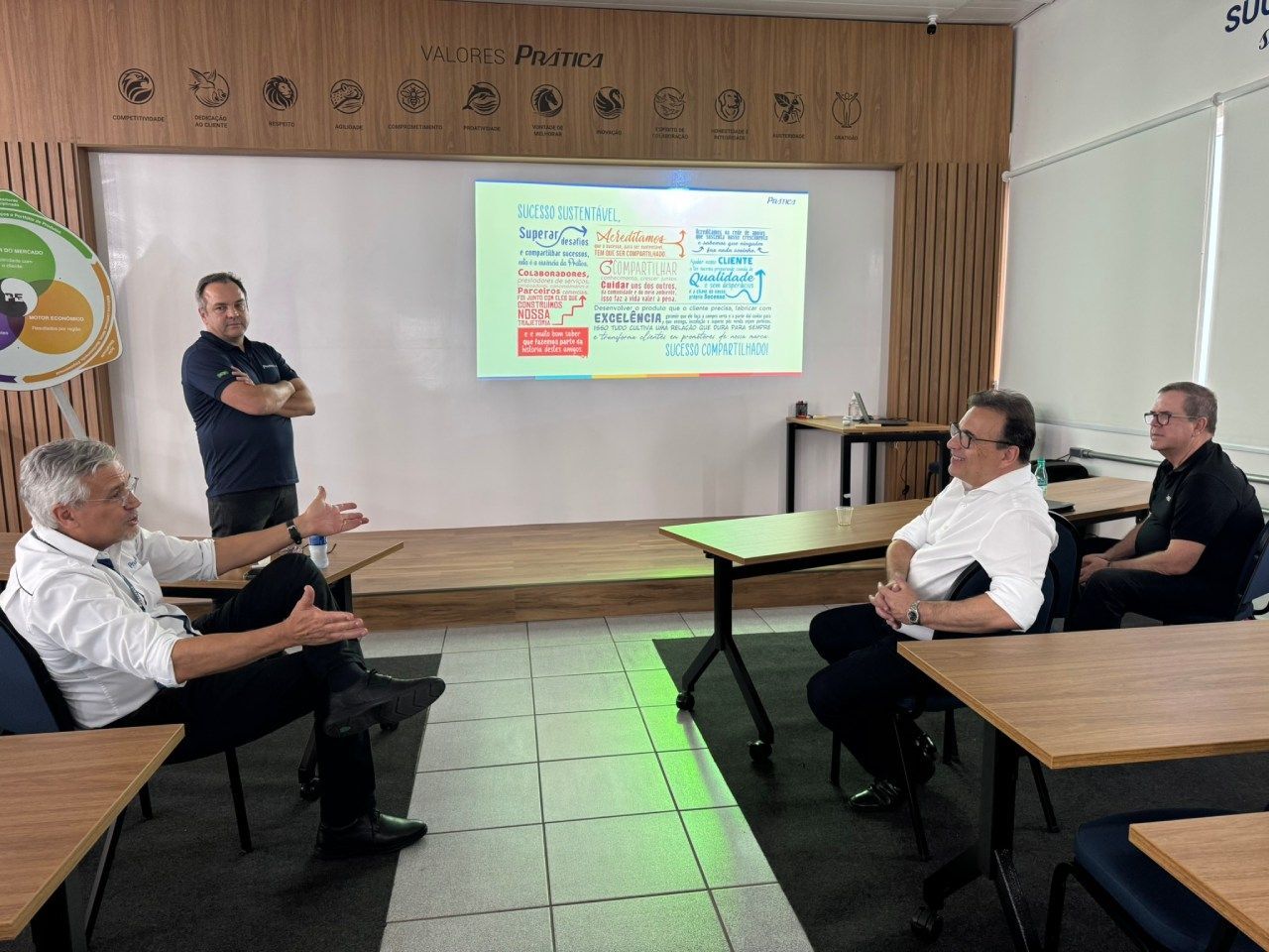 Um grupo de homens está sentado em mesas em frente a uma tela de projetor.