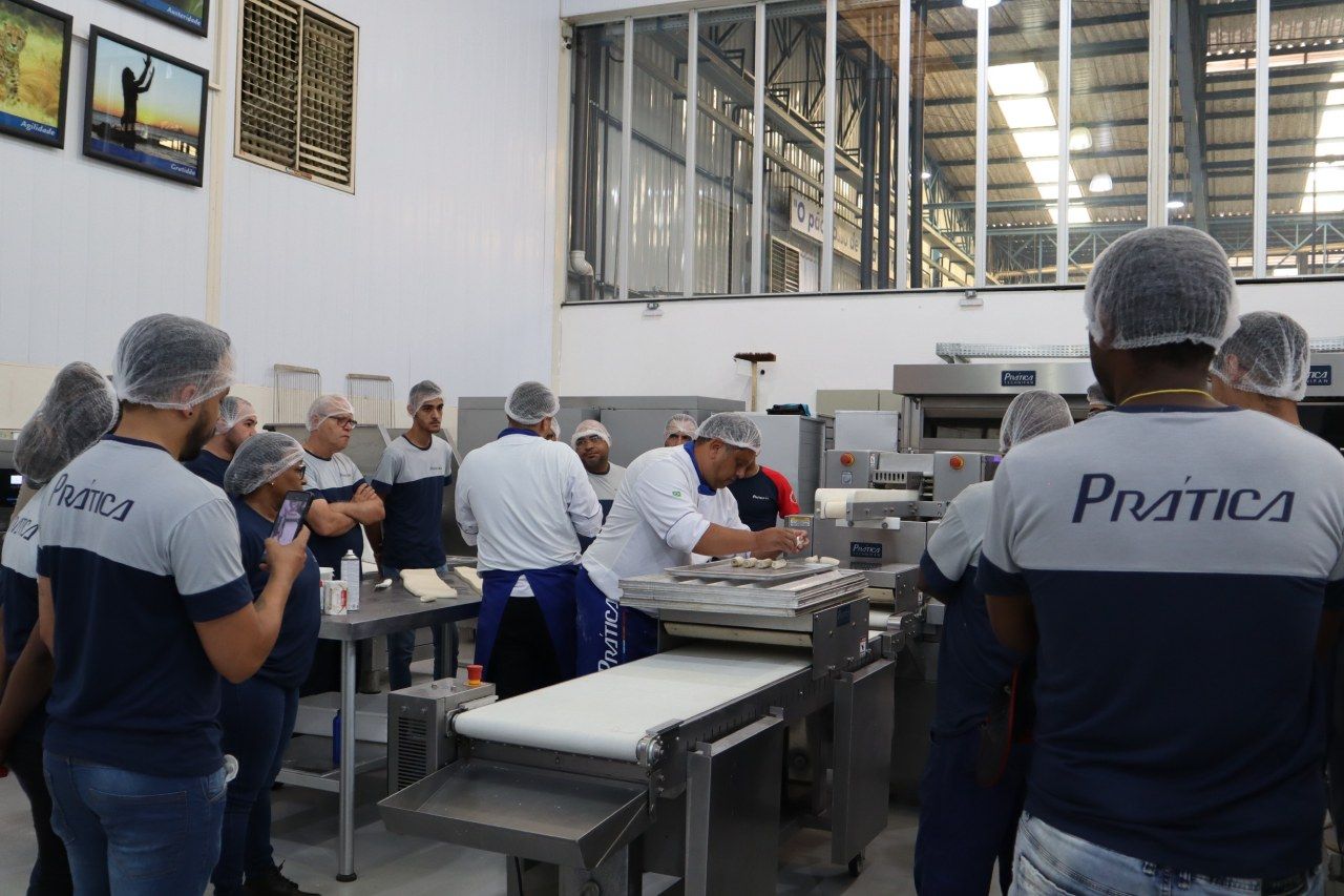 Um grupo de pessoas está em volta de uma máquina em uma fábrica.