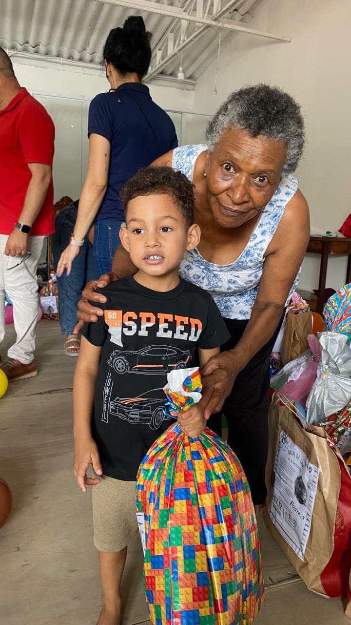 Uma mulher está parada ao lado de um menino segurando uma sacola de brinquedos.