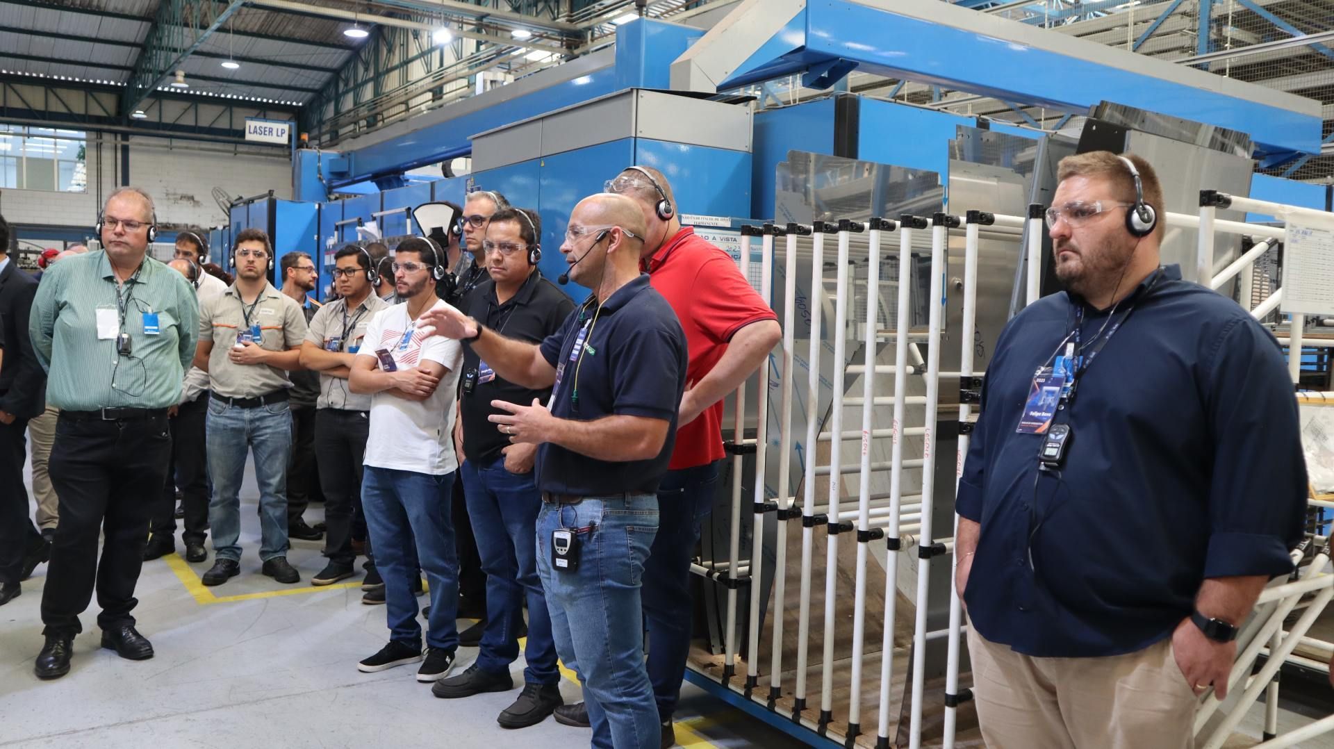 Um grupo de homens está em uma fábrica conversando entre si.