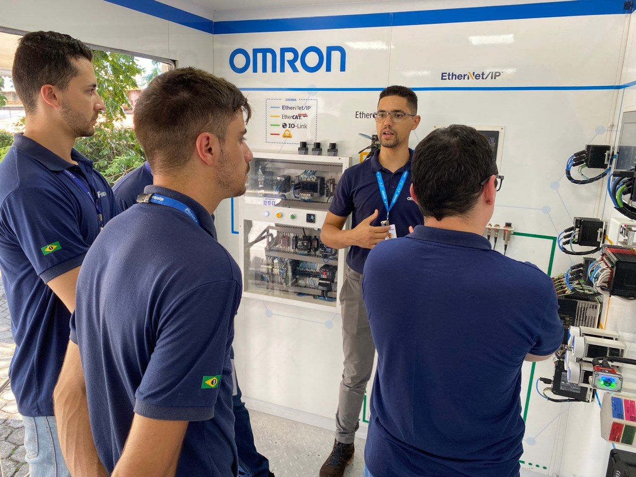 Um grupo de homens está parado em frente a uma parede com a palavra omron escrita nela.