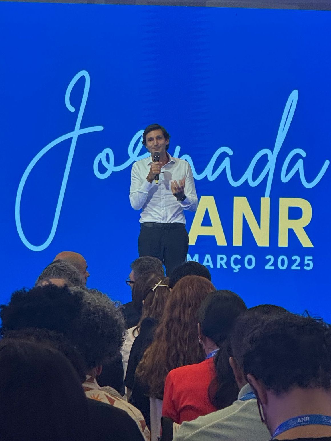 Um homem está fazendo um discurso em frente a uma placa que diz jornada anr