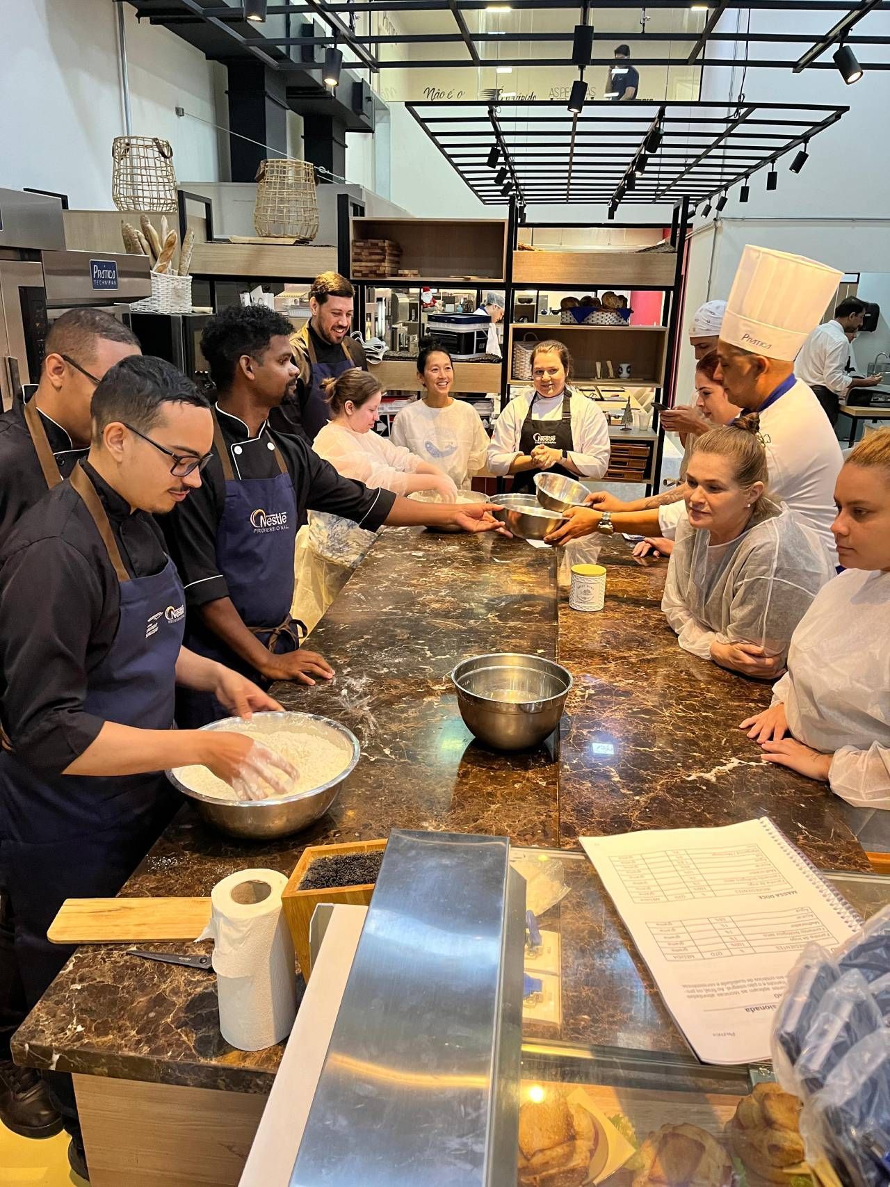 Um grupo de pessoas está sentado à mesa em uma cozinha preparando comida.