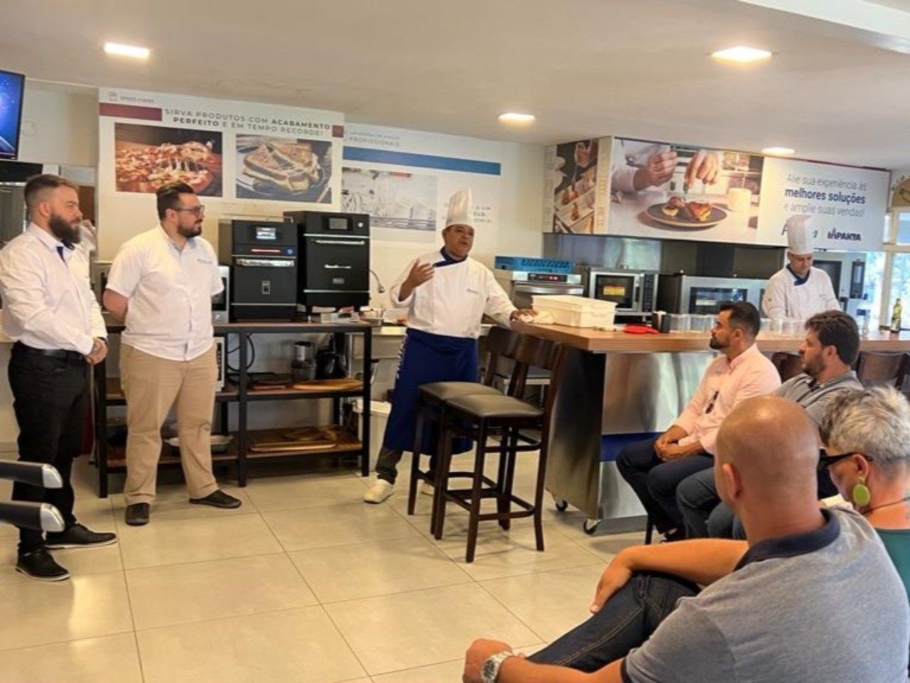 Um grupo de homens está sentado ao redor de uma mesa na cozinha.