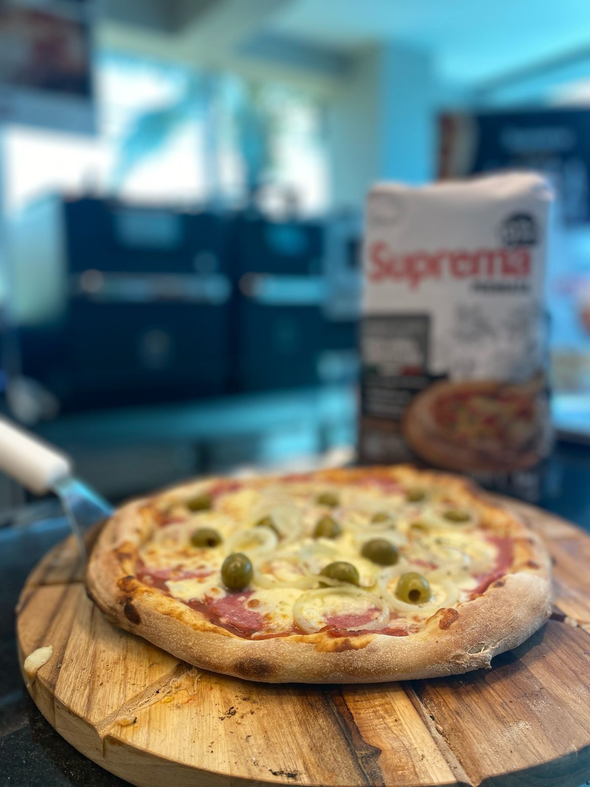 Uma pizza está em cima de uma tábua de corte de madeira.