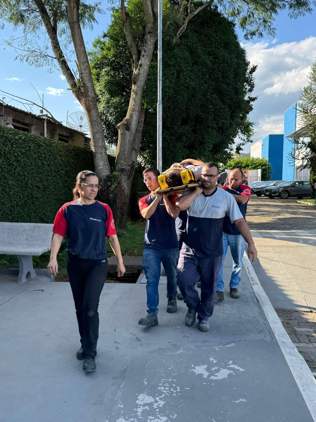 Um grupo de pessoas está caminhando pela calçada carregando uma pessoa em uma maca.