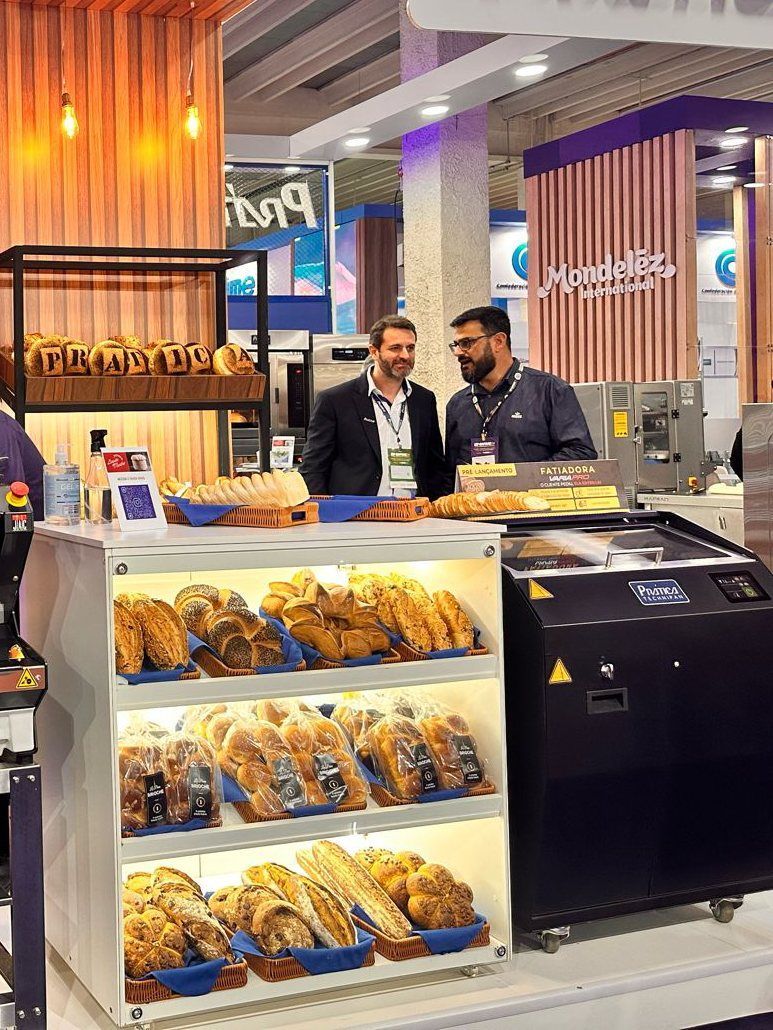 Dois homens estão em pé em frente a uma vitrine cheia de pães.