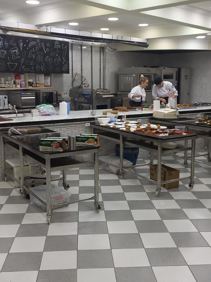 Uma cozinha com piso xadrez e mesas cheias de comida.