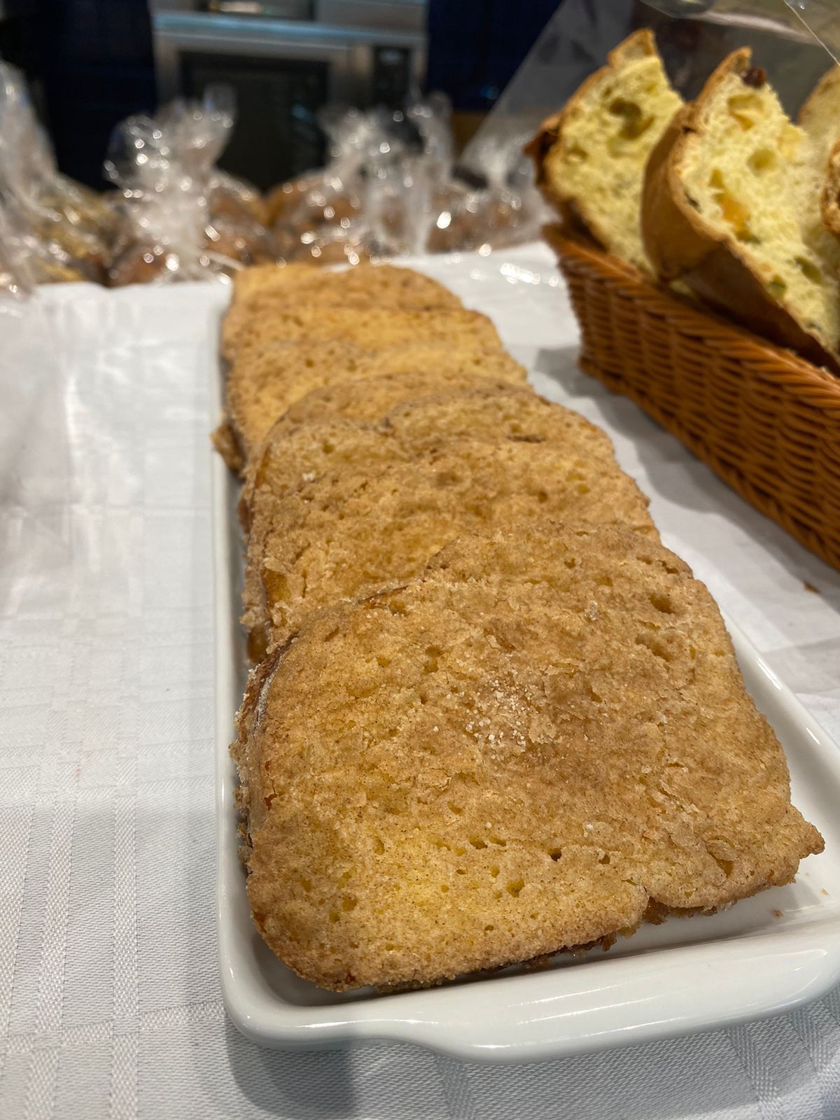 Uma bandeja de biscoitos está sobre uma mesa ao lado de uma cesta de pães.