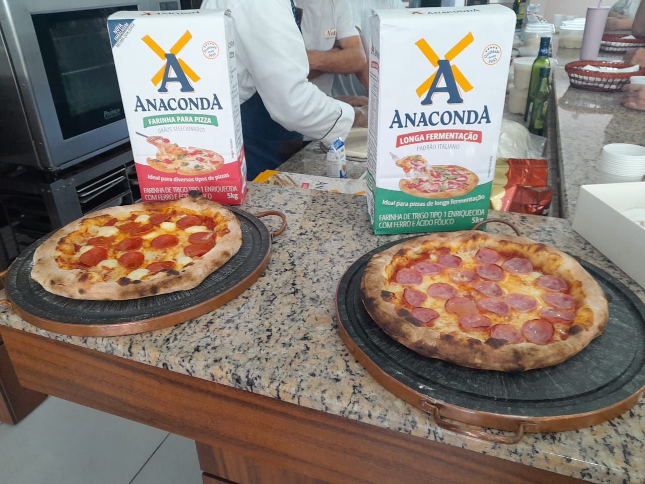 Duas pizzas em um balcão ao lado de duas caixas de anaconda