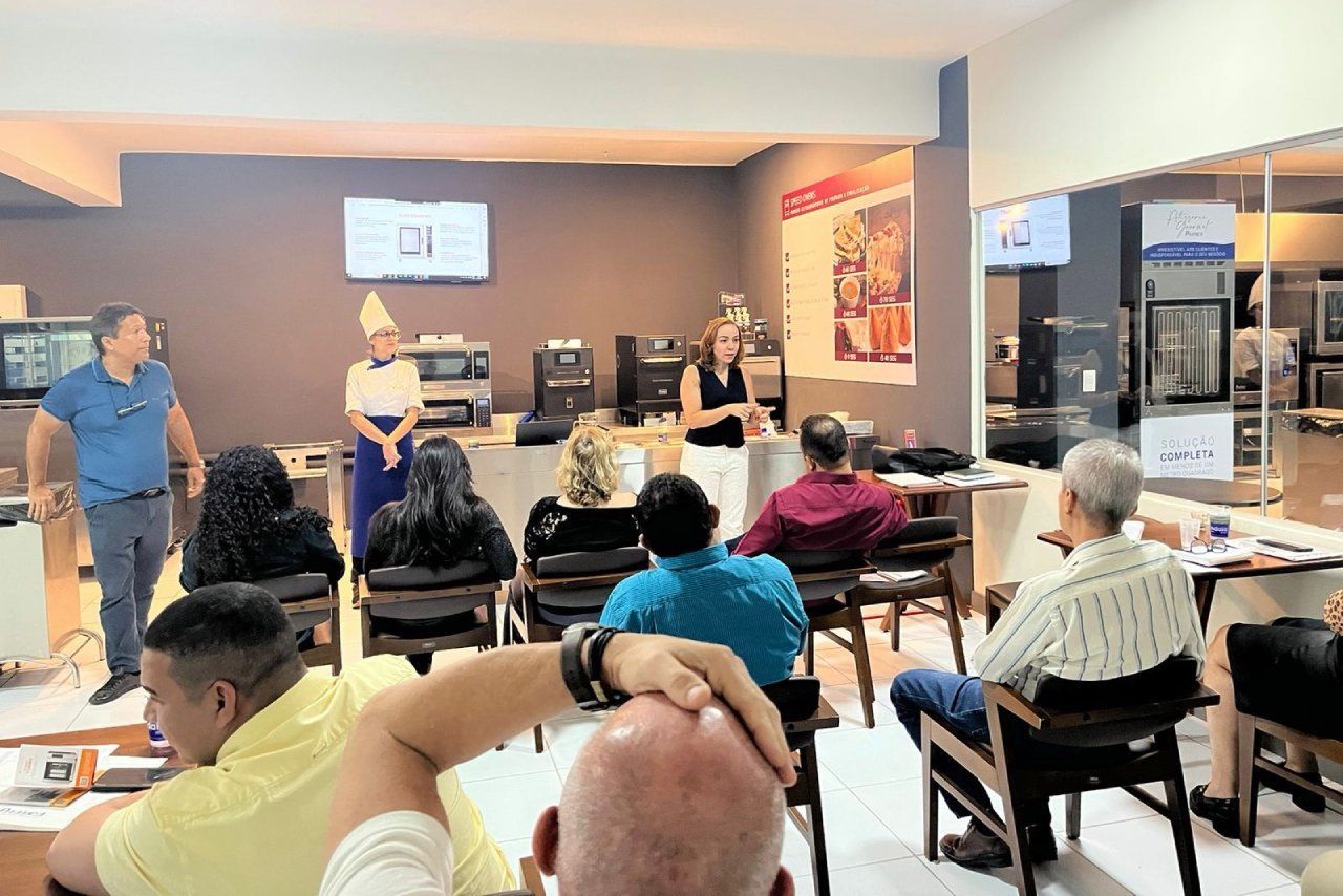Um grupo de pessoas está sentado em uma sala assistindo a uma apresentação.