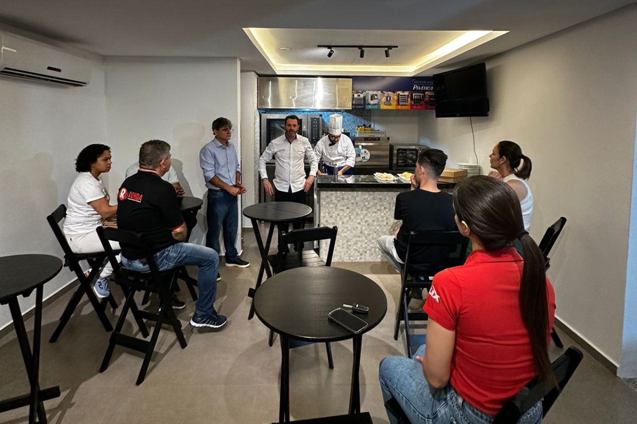 Um grupo de pessoas está sentado em mesas em uma sala.