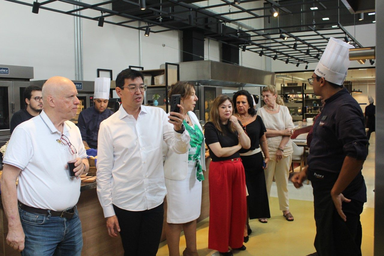 Um grupo de pessoas está em uma cozinha conversando com um chef.