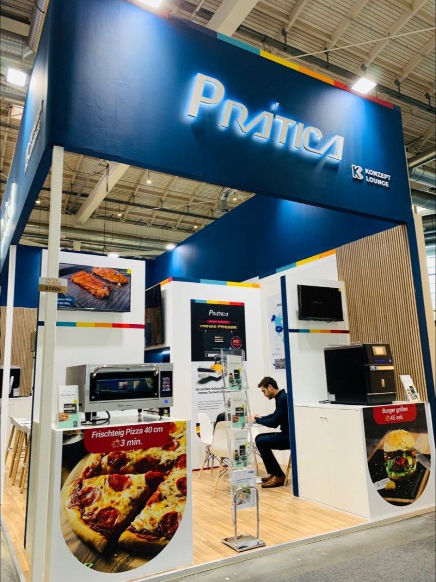 Um homem está sentado em um balcão sob uma placa que diz pratica