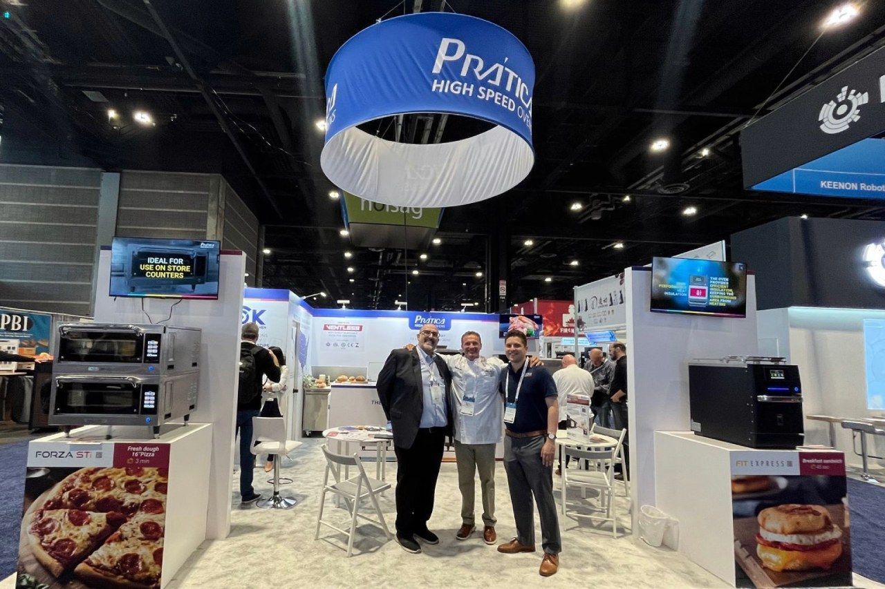 Um grupo de homens está em frente a um estande em uma convenção.