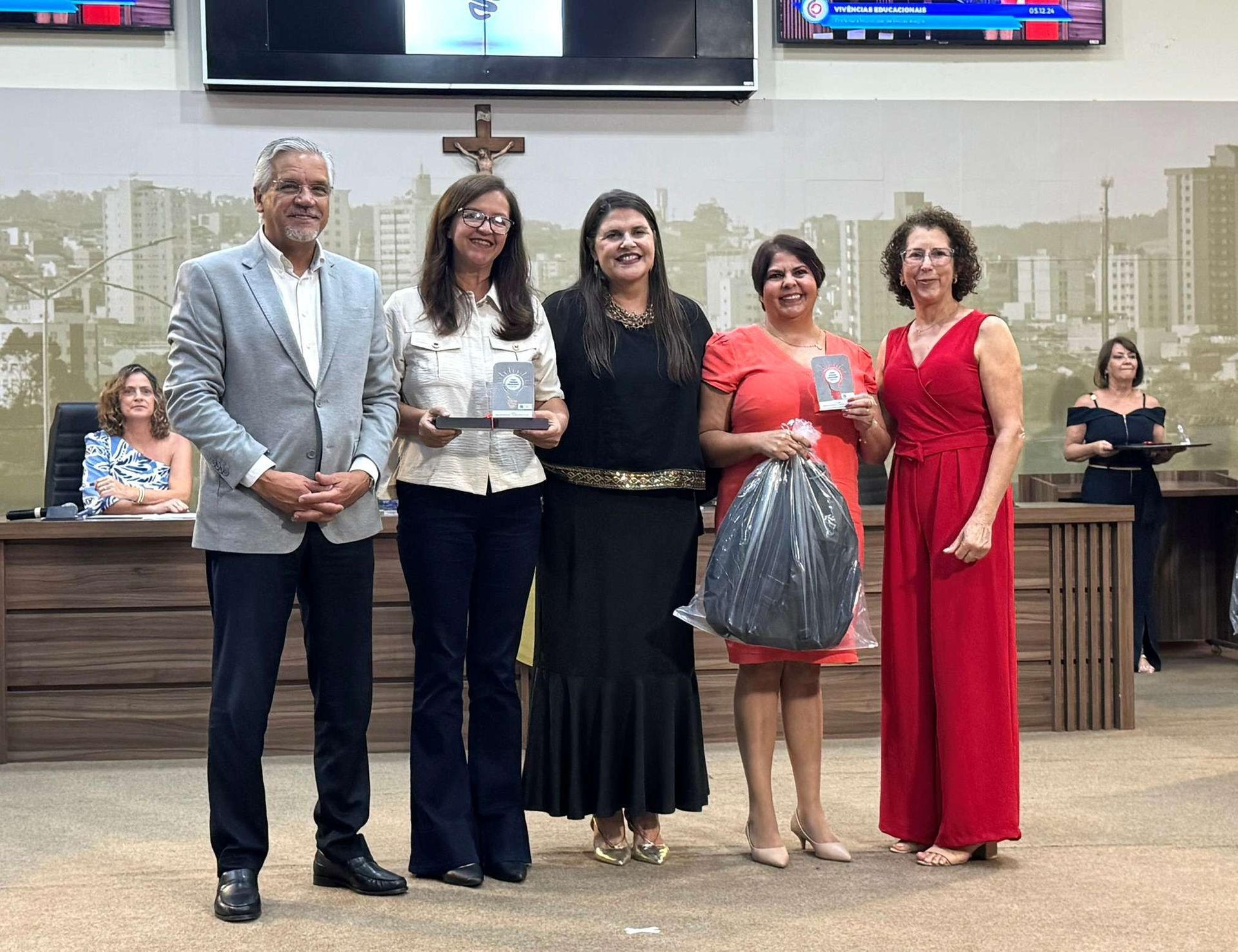 Um grupo de mulheres estão de pé, uma ao lado da outra, em uma sala.