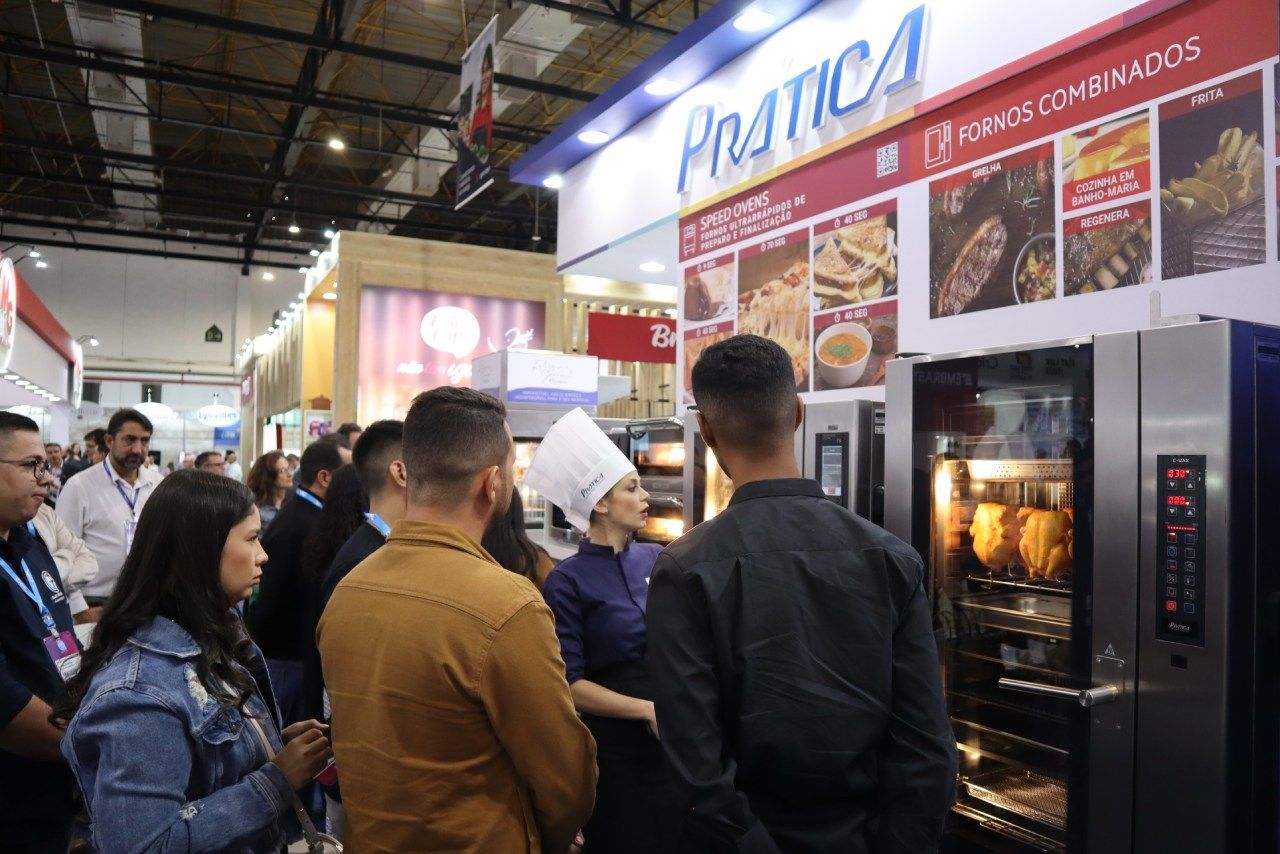 Um grupo de pessoas está em frente a um forno em uma padaria.