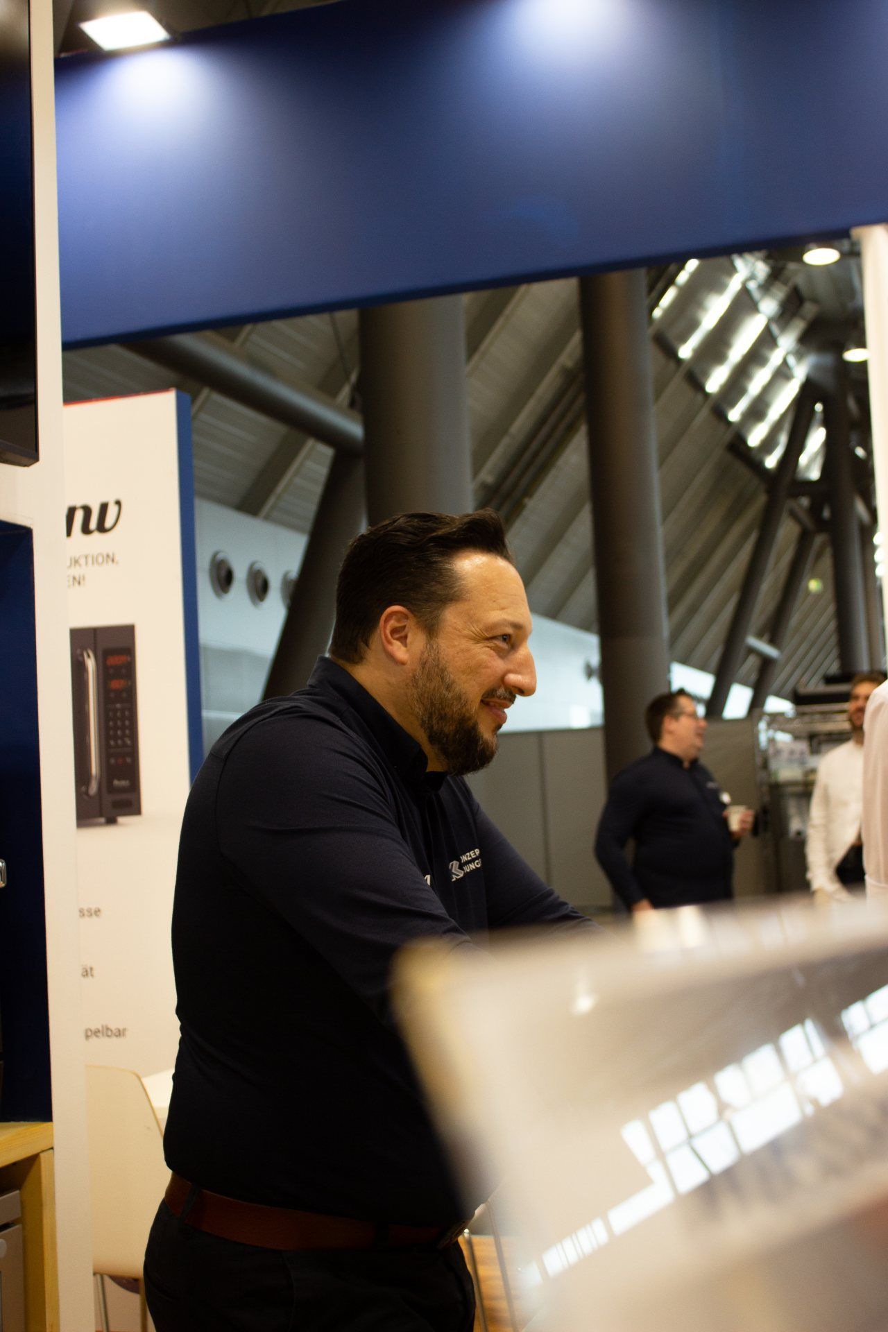 Um homem com barba está sentado em frente a um laptop.