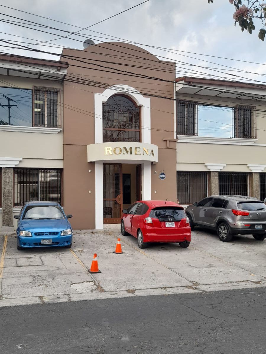 Dois carros estão estacionados em frente a um prédio que diz romera