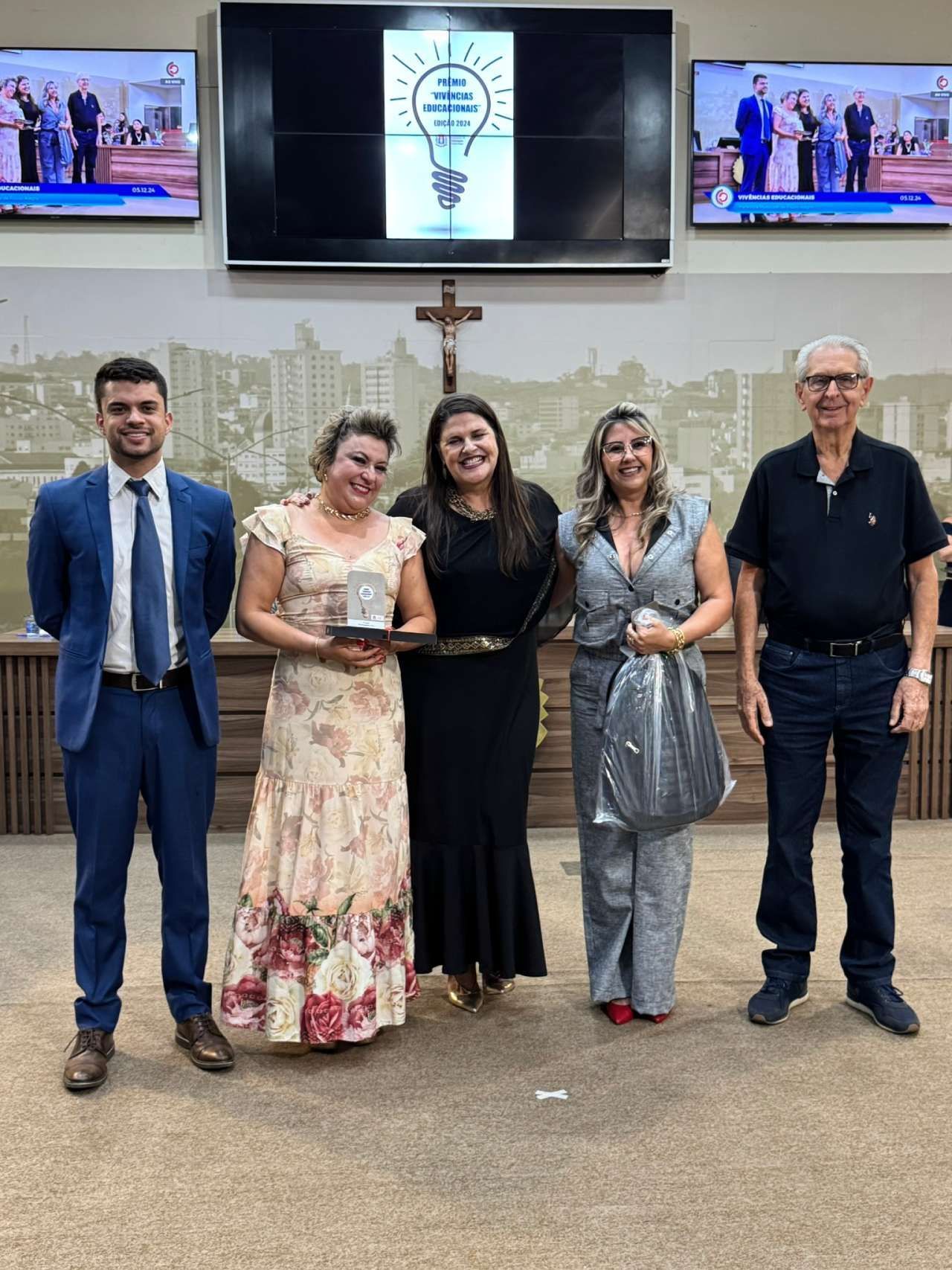 Um grupo de pessoas está de pé, uma ao lado da outra, em uma sala.