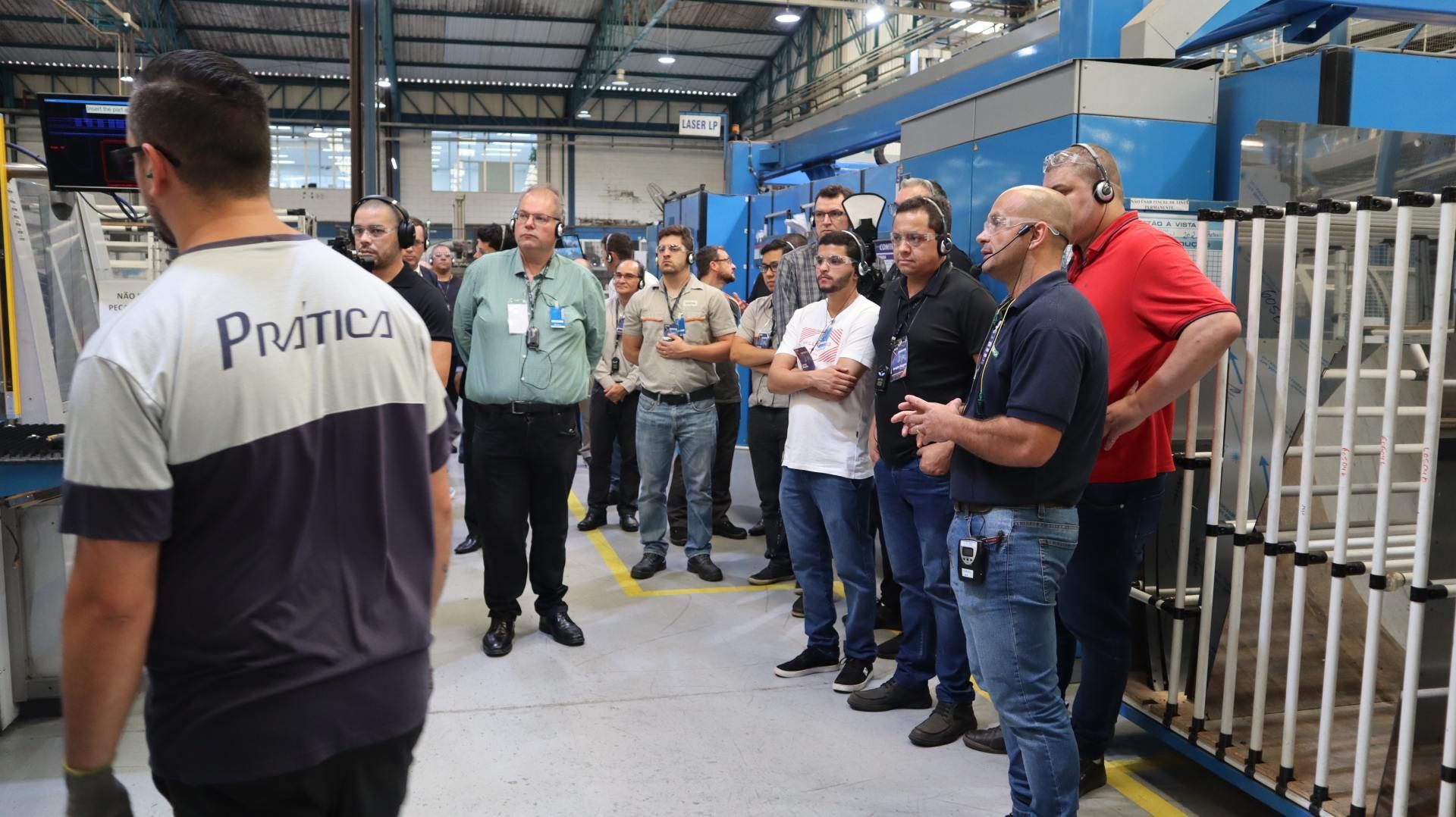 Um grupo de homens está em uma fábrica conversando entre si.