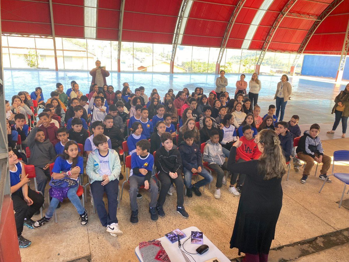 Uma mulher está parada na frente de um grande grupo de crianças.