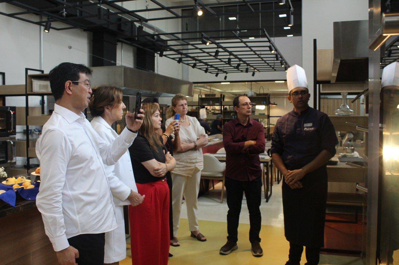 Um grupo de pessoas está em uma cozinha conversando entre si.