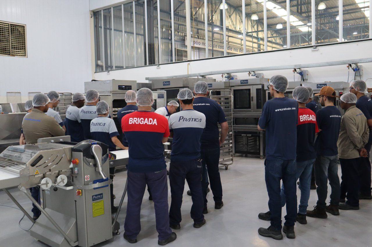 Um grupo de pessoas está em uma sala com um homem vestindo uma camisa vermelha que diz 'brigada' nela