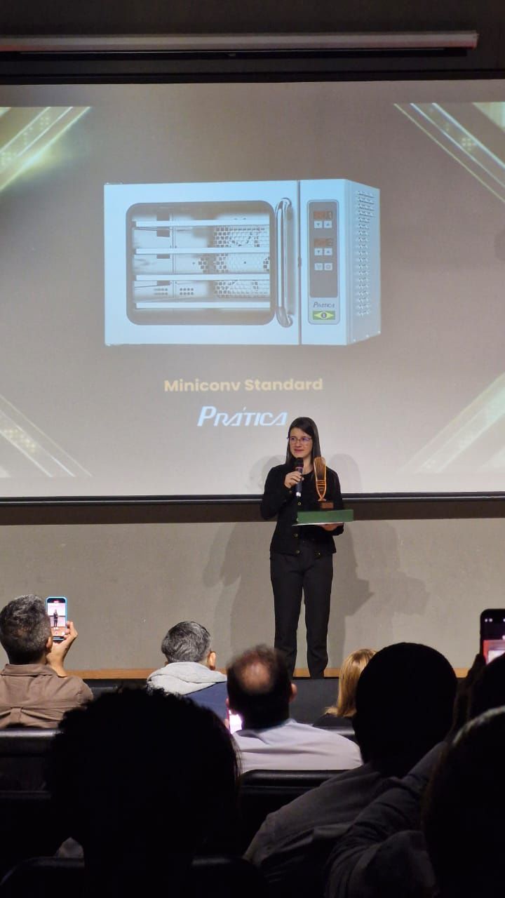 Uma mulher está em frente a uma tela de projetor com a imagem de um micro-ondas nela