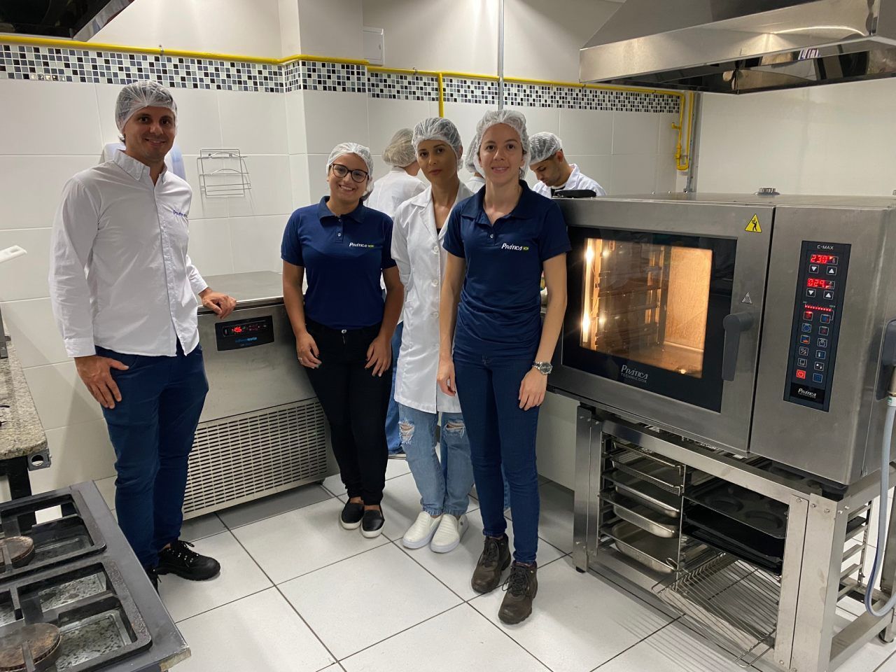 Um grupo de pessoas está em frente a um forno em uma cozinha.