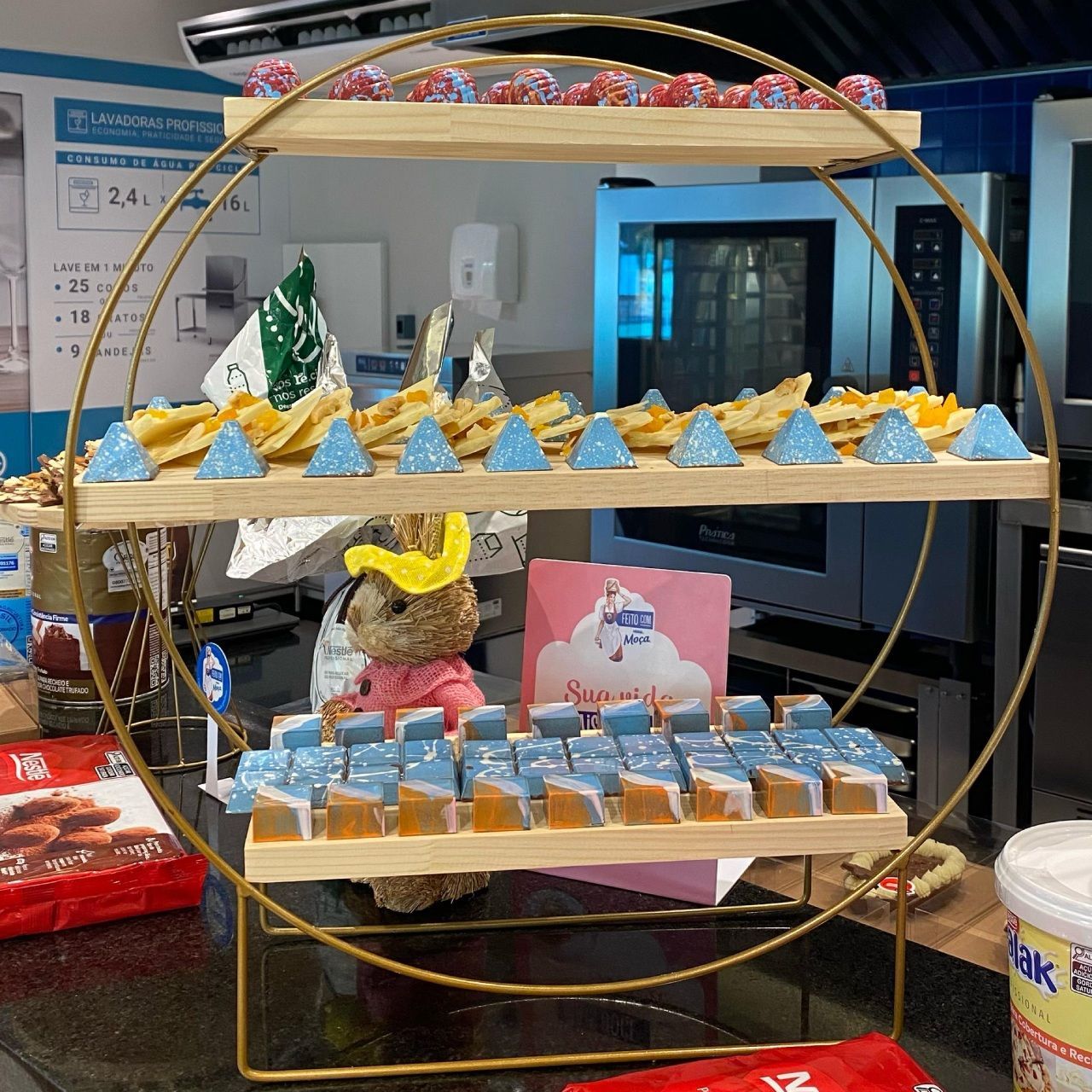 Um ursinho de pelúcia está sentado em uma mesa ao lado de uma exposição de comida