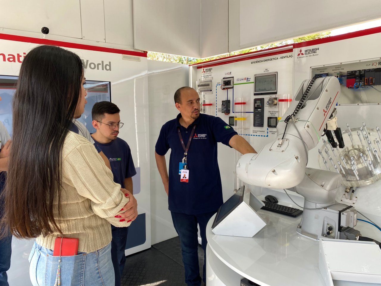 Um grupo de pessoas está olhando para um braço robótico em uma sala.