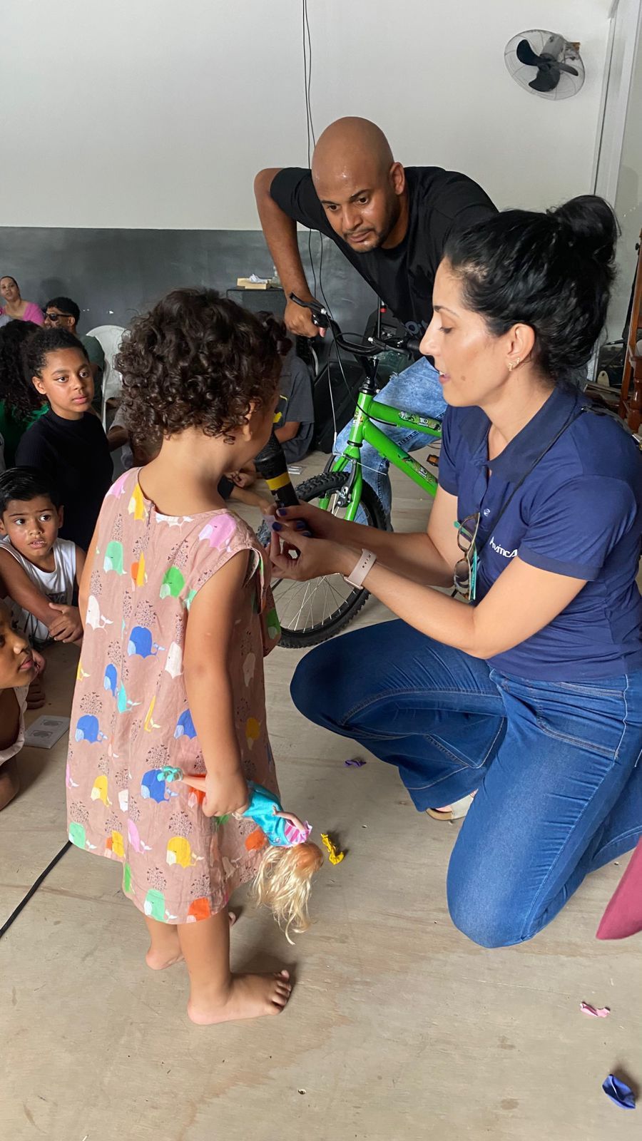 Uma mulher está ajoelhada ao lado de uma menina em uma sala.