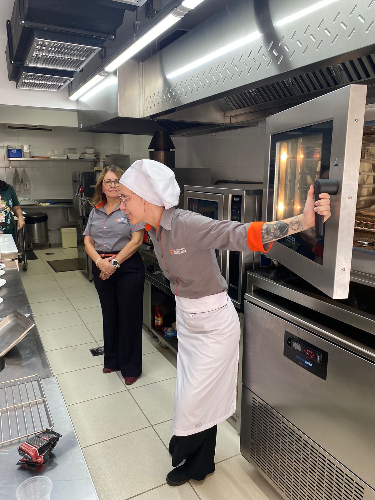 Uma mulher está parada na cozinha olhando para um forno.