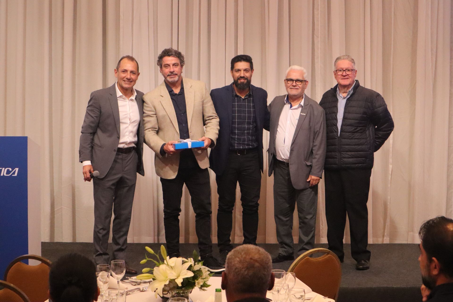 Um grupo de homens estão de pé, um ao lado do outro, em um palco.