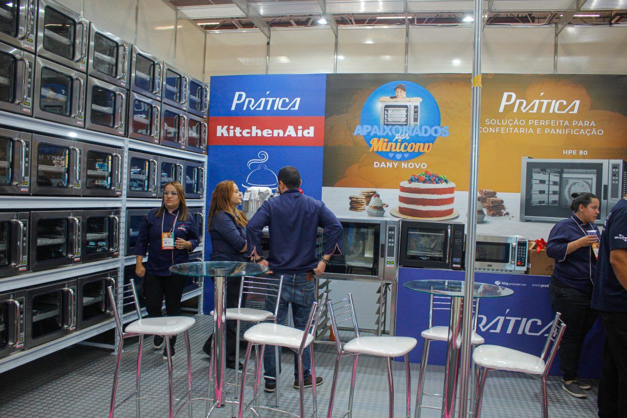 Um grupo de pessoas em pé na frente de uma placa da KitchenAid