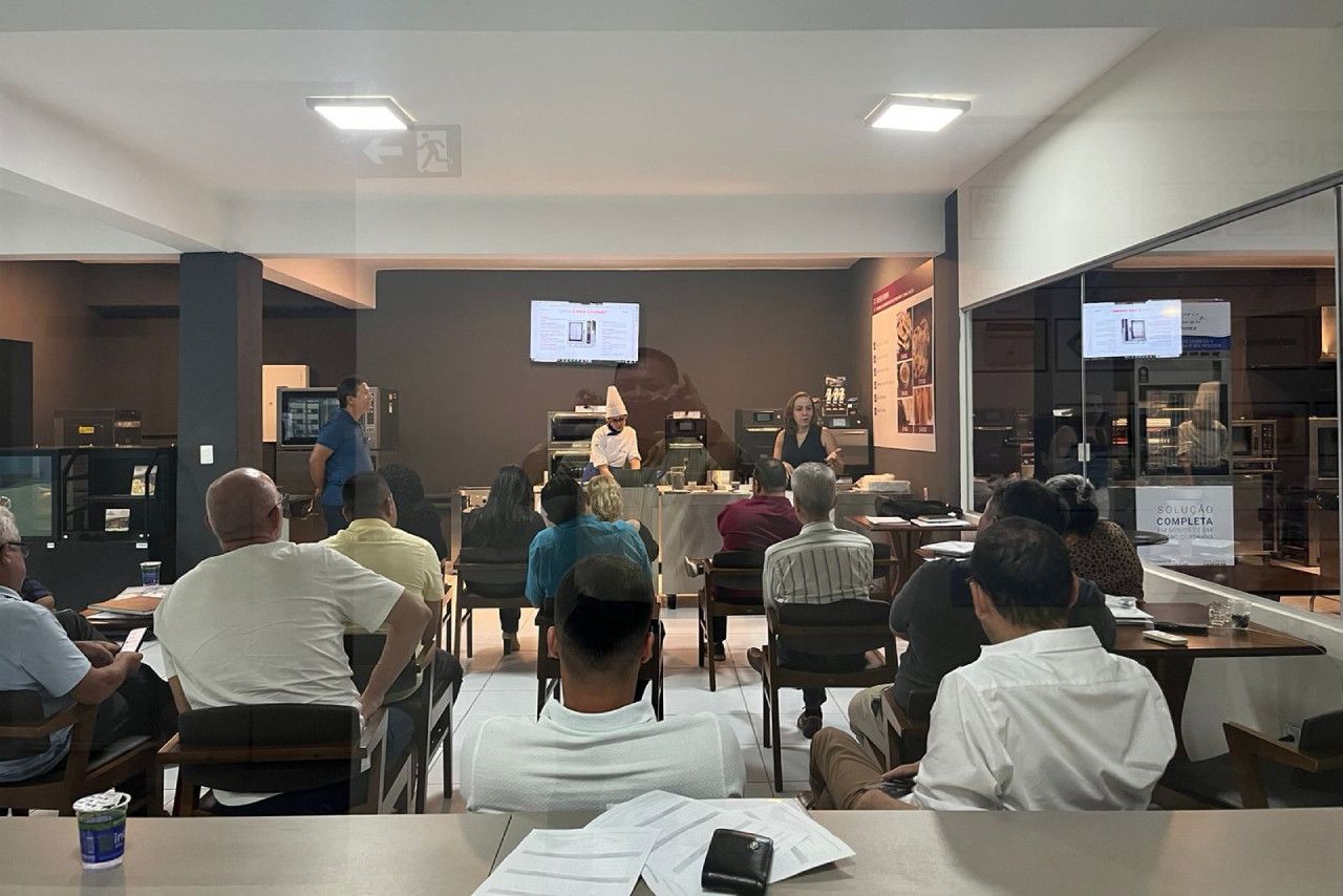 Um grupo de pessoas está sentado em uma sala assistindo a uma apresentação.